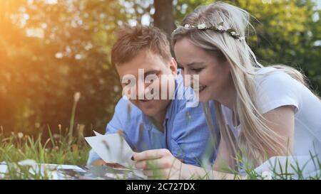 Un gars et une fille regardent un album de famille avec des photos dans le parc sur l'herbe. Banque D'Images