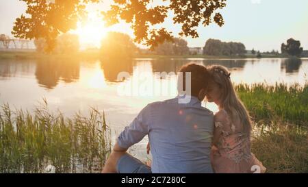 Un jeune couple est assis sur un lac au coucher du soleil. Banque D'Images