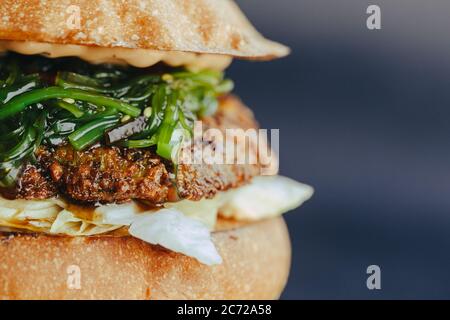 Circulaire Burger. Hamburger au fromage avec viande grillée, fromage, salade et rondelles d'oignon. Gros plan de délicieux hamburgers maison frais sur fond bleu écorce Banque D'Images