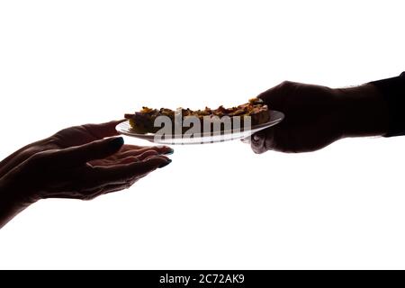 Jeune homme donne une pizza sur plat à une femme âgée dans sa main - silhouette, aide concept Banque D'Images