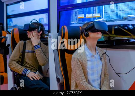 MOSCOU, RUSSIE - 25 JUIN 2019 : VR EXPO. Femme et homme utilisant un casque de réalité virtuelle noir et jouant en passager de simulateur de transport public à Banque D'Images