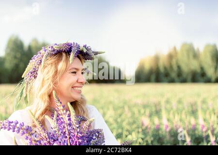 Une belle, heureuse fille appréciant un champ lupin dans un pré, se détendre en plein air, s'amuser, tenant une plante. Le concept de l'harmonie, du bonheur, Banque D'Images