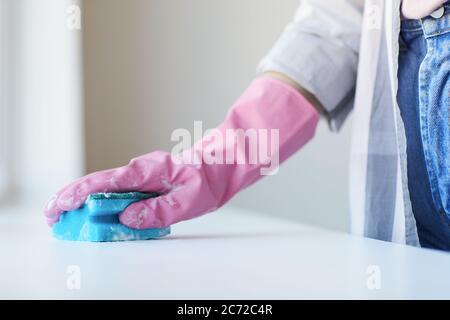 Gros plan de la femme avec des gants en caoutchouc et une éponge pour nettoyer la table Banque D'Images
