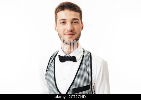 Portrait d'un jeune serveur souriant avec une barbe en nœud papillon, regardant avec un arrière-plan blanc dans l'appareil photo Banque D'Images