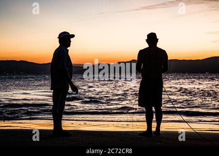 Silhouette de deux pêcheurs sur la rive de la plage de Daniela. Florianopolis, Santa Catarina, Brésil. Banque D'Images