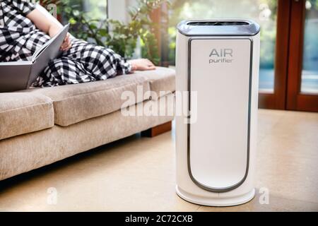 Le purificateur d'air nettoie l'air. Le purificateur d'air moderne nettoie l'air dans le salon avec une femme couché sur le canapé. Le logo sur l'appareil a été créé dans Banque D'Images