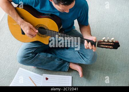 Homme de lecture de guitare acoustique de la musique de fond d'appartement Banque D'Images