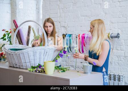 Deux artistes fleuristes professionnels, fleuristes en train de réaliser un grand panier floral avec des fleurs à l'atelier, fleuriste. Fleuriste, fait main, mariage Banque D'Images