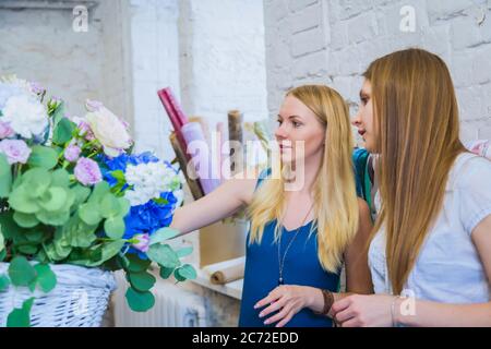 Deux artistes fleuristes professionnels, fleuristes en train de réaliser un grand panier floral avec des fleurs à l'atelier, fleuriste. Fleuriste, fait main, mariage Banque D'Images