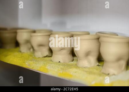 Mugs infinis dans la rangée sur l'étagère de l'atelier de poterie, studio de céramique - vue rapprochée. Création, bricolage, art et concept fait main Banque D'Images