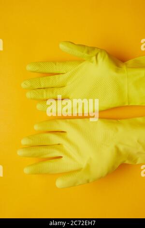 Gros plan de gants en caoutchouc jaune isolés sur fond jaune Banque D'Images