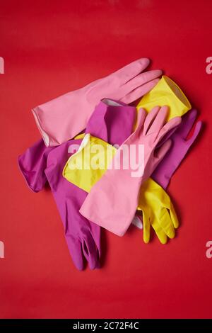 Vue à grand angle des gants en caoutchouc colorés pour le nettoyage isolés sur fond rouge Banque D'Images