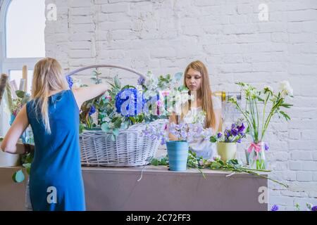 Deux artistes fleuristes professionnels, fleuristes en train de réaliser un grand panier floral avec des fleurs à l'atelier, fleuriste. Fleuriste, fait main, mariage Banque D'Images