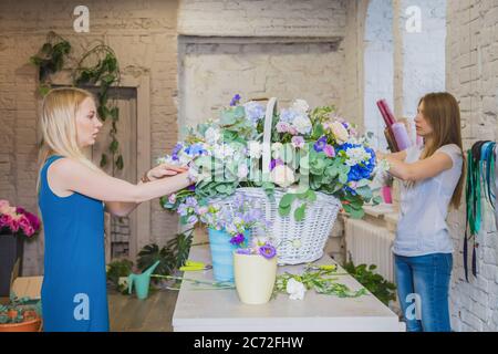 Deux artistes fleuristes professionnels, fleuristes en train de réaliser un grand panier floral avec des fleurs à l'atelier, fleuriste. Fleuriste, fait main, mariage Banque D'Images