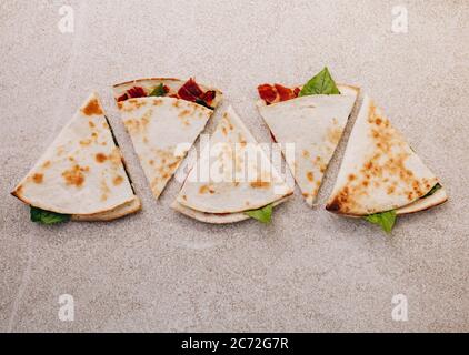 Pita à pain plat rempli de jambon, de légumes et de sauce sur une planche ronde en bois - vue du dessus. Banque D'Images