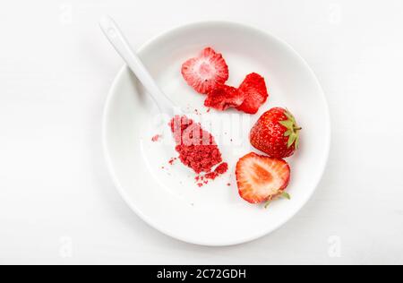 Poudre de fraise composée de fraises lyophilisées pour saupoudrer. Ingrédient de saveur et de couleur pour les aliments. Vue de dessus, fond blanc minimal, espace de copie Banque D'Images