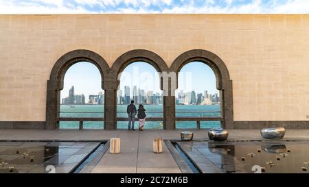 Doha, Qatar - février 2019 : couple regardant les gratte-ciel de Doha à travers les arches du Musée d'art islamique, Qatar Banque D'Images