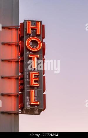 Le panneau de l'hôtel au néon est situé à l'angle du bâtiment, contre le ciel du coucher du soleil Banque D'Images