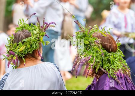 Femmes non identifiées dans des robes traditionnelles avec des couronnes de solstice d'été faites à partir de fleurs de champ, de graminées et de céréales. Banque D'Images