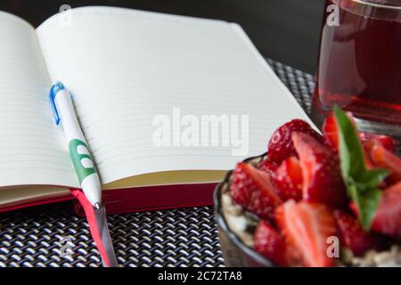 journal de nourriture ouvert pour le régime, bol de flocons d'avoine avec fraises fraîches. Le concept de saine alimentation, contrôle du poids. Banque D'Images