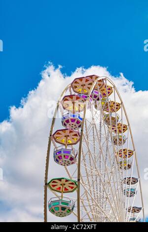 Grande roue par une journée ensoleillée avec ciel bleu et nuage en arrière-plan. Banque D'Images