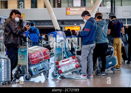 Les voyageurs portant un masque facial ont été vus attendre avec leurs bagages à l'aéroport.c'est encore un voyage d'affaires à l'aéroport de Schiphol car les gens voyagent pendant les vacances d'été, mais avec le port obligatoire de masques faciaux. La compagnie aérienne KLM a reçu un soutien de 3.4 milliards d'euros en raison de l'impact de la crise du coronavirus sur l'aéroport. Banque D'Images