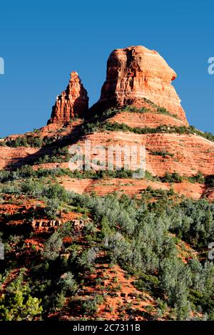 Des arbres de genévrier et des formations de roches rouges contre un ciel bleu dans la région de Sedona, dans le nord de l'Arizona. Banque D'Images