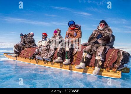 Visiteurs et aînés inuits locaux, vêtus de vêtements traditionnels en peau de caribou, assis sur un traîneau traditionnel inuit, également appelé komatik. Banque D'Images