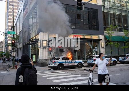 Un croiseur de police de Chicago brûle à l'extérieur de l'AMC Theatre sur Ohio Street à Chicago alors que les gens prennent des séquences téléphoniques le 30 mai 2020. Une manifestation Black Lives Matter a attiré des milliers de personnes à Chicago samedi dans le cadre d'une journée nationale de protestation contre les récents meurtres de George Floyd à Minneapolis, Ahmaud Arbery à Atlanta et Breonna Taylor à Louisville. Au cours de la journée, les groupes se sont divisés, un nombre limité de personnes se sont rendu dans les magasins du centre-ville et sur le Magnificent Mile. (Photo de Max Herman) Banque D'Images