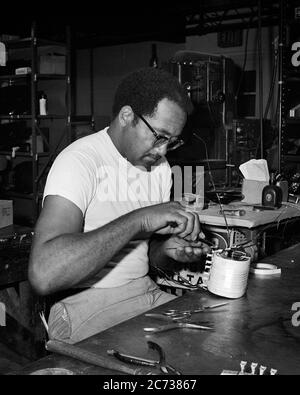 ANNÉES 1960, HOMME QUALIFIÉ, AFRO-AMÉRICAIN, TECHNICIEN ÉLECTRIQUE, RECONSTRUCTION D'UN COMPOSANT DE MACHINE INDUSTRIELLE EN ATELIER - I5239 HAR001 HARS B&W SUCCÈS COMPÉTENCES MÉTIER FORCE SERVICE CLIENT AFRO-AMÉRICAINS AFRO-AMÉRICAINS CARRIÈRES SAVOIR PROGRÈS PUISSANT ORIGINE ETHNIQUE NOIRE INNOVATION FIERTÉ DANS L'OPPORTUNITÉ EMPLOIS DE FABRICATION RÉPARATION DE COMPOSANT IMAGINATION CONCEPTUELLE CRÉATIVITÉ ÉLÉGANTE COMPÉTENCES MI-ADULTES HOMME DE PRÉCISION HOMME MOYEN-ADULTE CONCENTRATION NOIR ET BLANC HAR001 OLD FASHIONED AFRO-AMÉRICAINS Banque D'Images