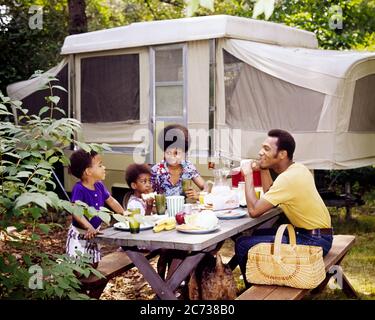 LES ANNÉES 1970 SOURIANTES FAMILLE AFRO-AMÉRICAINE MANGER ENSEMBLE À TABLE DE PIQUE-NIQUE DEVANT LA CABINE DE CAMPING - KC5134 PHT001 HARS MOM NOSTALGIQUE PAIRE 4 COULEUR MÈRES VIEUX TEMPS NOSTALGIE BANDE-ANNONCE VIEILLE MODE 1 JEUNE COMMUNICATION JEUNES ADULTES ENFANTS FAMILLES JOIE STYLE DE VIE SATISFACTION FEMMES MARIÉES CONJOINT RURAL ÉPOUX SAINTETÉ COPIE ESPACE AMITIÉ DEMI-LONGUEUR FEMMES FILLES PERSONNES MÂLES CAMPING TRANSPORT PÈRES PARTENAIRE ÉTÉ LIBERTÉ BONHEUR GRAND ANGLE AVENTURE LOISIRS AFRO-AMÉRICAINS DADS RÉCRÉATION NOIR ETHNICITÉ CONNEXION POP-UP CAMPEUR BÉBÉ GARÇON COOPÉRATION Banque D'Images