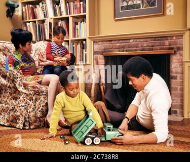 ANNÉES 1970 FAMILLE AFRO-AMÉRICAINE DANS LA SALLE DE SÉJOUR HOMME ET GARÇON SUR LE SOL AVEC CAMION FEMME ET FILLE SUR LA CHAISE AVEC POUPÉE - KJ5144 PHT001 HARS QUATRE MEUBLES MOM INTÉRIEUR PLANCHER ETHNIQUE NOSTALGIQUE 4 SUBURBAN COULEUR URBAINE RELATION MÈRES VIEUX TEMPS NOSTALGIE FRÈRE CHAISES VIEILLE MODE SOEUR JUVÉNILE VÉHICULE FAMILLES JOIE STYLE DE VIE SATISFACTION PARENTALITÉ FEMMES FRÈRES RELATION ÉPOUX ADULTES VIE VIE TRANSPORT COPIE ESPACE PERSONNES ENFANTS AMITIÉ DEMI-LONGUEUR PERSONNES INSPIRATION ADULTES HOMMES FRÈRES FRÈRES FRÈRES FRÈRES FRÈRES SŒURS AMÉRICAINS TRANSPORT PÈRES MARI ET FEMME HOMMES ET FEMMES ÉPOUX ET FEMMES FEMMES FEMMES FEMME FEMME AU FOYER Banque D'Images