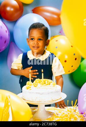 ANNÉES 1970 SOURIRE GARÇON AFRO-AMÉRICAIN MAIN À LA POITRINE AVEC DES BALLONS DE COULEUR PASTEL GÂTEAU D'ANNIVERSAIRE AVEC TROIS BOUGIES GLAÇAGE JAUNE - KJ5640 PHT001 HARS COPIER ESPACE MI-LONGUEUR HOMMES GIVRANT BONHEUR JOYEUX AFRO-AMÉRICAINS EXCITATION AFRO-AMÉRICAINE NOIR FIERTÉ ETHNIQUE SOURIRES CONCEPTUEL COLORÉ JOYEUX CROISSANCE JUVÉNILES PASTEL VIEUX MODÉ AFRO-AMÉRICAINS Banque D'Images