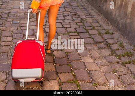 Pieds d'une fille roulant une valise sur le trottoir. Tourisme. Banque D'Images