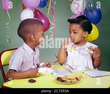 ANNÉES 1960, GARÇON AFRO-AMÉRICAIN ET FILLE PARTAGEANT DE LA CRÈME GLACÉE ET DES BISCUITS À LA FÊTE D'ANNIVERSAIRE - KN530 HAR001 HARS STREAMERS STUDIO TOURNÉ MAISON VIE COPIE ESPACE AMITIÉ MÂLES COOKIES FRÈRES ET SŒURS TÊTE ET ÉPAULES GRAND ANGLE AFRO-AMÉRICAINS AFRO-AMÉRICAINS ET L'EXCITATION NOIR ETHNICITÉ PARTIES FRÈRE CONNEXION AMICALE DE CRÈME GLACÉE CROISSANCE JUVÉNILES ENSEMBLE HAR001 AFRO-AMÉRICAINS À L'ANCIENNE Banque D'Images