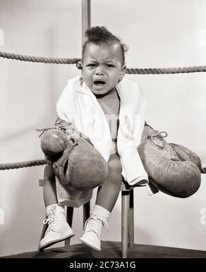 ANNÉES 1950 VOCAL AFRO-AMÉRICAIN BÉBÉ GARÇON COMBATTANT PORTANT DES GANTS DE BOXE ASSIS SUR L'ANNEAU DE BOXE TABOURET D'ANGLE PLEURANT REGARDANT L'APPAREIL PHOTO - N40 CRS001 HARS MAISON VIE ATHLÉTISME COPIER ESPACE PLEINE LONGUEUR PHYSIQUE FORME RISQUE COIN EXPRESSIONS ATHLÉTIQUES B&W ŒIL CONTACT RÉUSSITE ACTIVITÉ PHYSIQUE CHASSEUR FORCE VICTOIRE STRATÉGIE AFRO-AMÉRICAINE COURAGE EXCITATION AFRO-AMÉRICAINE FAIBLE ANGLE PUISSANT VOCAL NOIR ETHNICITÉ FIERTÉ SUR LES PROFESSIONS ATHLÈTES CONCEPTUELS FLEXIBILITÉ MUSCLES BÉBÉ GARÇON NOIR ET BLANC ANCIEN MODÈLE AFRO-AMÉRICAIN Banque D'Images