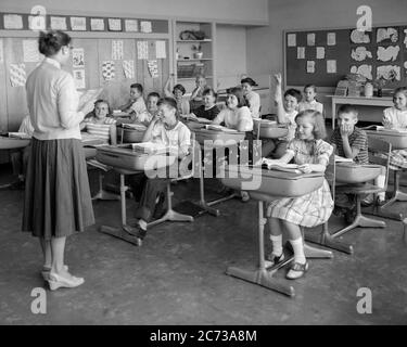 ANNÉES 1950 19560 SALLE DE CLASSE ÉLÉMENTAIRE ENSEIGNANT DE L'ÉCOLE DE RETOUR À LA CAMÉRA ÉLÈVES GARÇONS FILLES AU BUREAU MAINS LEVÉES - S12002 HEL001 HARS VIE ÉLEVÉE FEMMES COPIER ESPACE PLEINE LONGUEUR DEMI-LONGUEUR FEMMES PERSONNES HOMMES ÉLEVER B&W BUREAUX ÉCOLES DÉCOUVERTE MANUELLE EXCITATION INSTRUCTEUR SAVOIR PROFESSIONS PRIMAIRE 1956 CONNEXION ÉDUCATEUR COOPÉRATION ÉDUCATEURS ÉDUCATION DE CLASSE MONITEURS DE CROISSANCE SCOLAIRE JEUNES ADULTES MOYENS FEMMES ADULTES MOYENS PRÉ-ADOLESCENTS PRÉ-ADOLESCENTS GARÇONS PRÉ-ADOLESCENTS FILLES ÉCOLE ENSEIGNE LA TOGETHNESS NOIR ET BLANC CAUCASIEN ETHNICITÉ ANCIENNE Banque D'Images