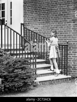 ANNÉES 1940 FILLE SOURIANTE MARCHANT DANS LES ESCALIERS DE BRIQUE MAISON PORTANT DES LIVRES SCOLAIRES PORTANT ROBE AVEC CARREAUX GARNITURE SELLE OXFORD CHAUSSURES - S3562 HEL001 HARS STYLE DE VIE SATISFACTION BRIQUE FEMMES MAISONS MAISON VIE COPIE ESPACE PLEINE LONGUEUR BÂTIMENTS RÉSIDENTIELS PLAID CONFIANCE B&W ÉCOLES GRADE BONHEUR GAI COIFFURE SAVOIR TAILLER MAISONS SOURIRES PRIMAIRES OXFORD JOYFUL RÉSIDENCE TRESSES TRESSE GRADE ÉCOLE CROISSANCE JEUNES PIGEONS AVANT-ADOLESCENCE FILLE SELLE OXFORD NOIR ET BLANC CAUCASIEN ORIGINE ETHNIQUE ANCIEN MODE Banque D'Images