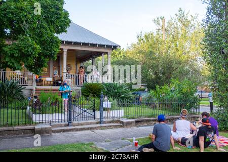 Nouvelle-Orléans, Louisiana/USA - 7/10/2020: Groupe jouant sur le porche avant de la maison dans le quartier chic avec une femme servant le melon d'eau aux voisins Banque D'Images