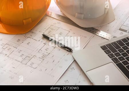 Gros plan des plans avec croquis de projets, ordinateur portable, casque et quelques outils mécaniques. Banque D'Images
