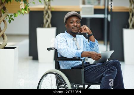 Portrait d'un homme africain handicapé assis en fauteuil roulant et utilisant une tablette numérique Banque D'Images