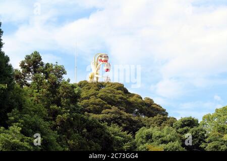 L'attraction de la roue de ferris de Rakuten-ji derrière les arbres à Beppu, Oita, Japon. En juin 2019. Banque D'Images