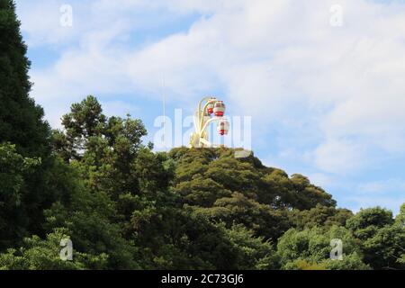 L'attraction de la roue de ferris de Rakuten-ji derrière les arbres à Beppu, Oita, Japon. En juin 2019. Banque D'Images