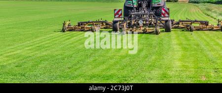 Tondeuse à gazon industrielle coupant l'herbe dans un grand champ agricole Banque D'Images