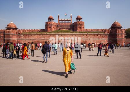 New Delhi / Inde - 19 février 2020 : jeune touriste asiatique en robe jaune posant devant les murs de fort Rouge avec la foule derrière Banque D'Images