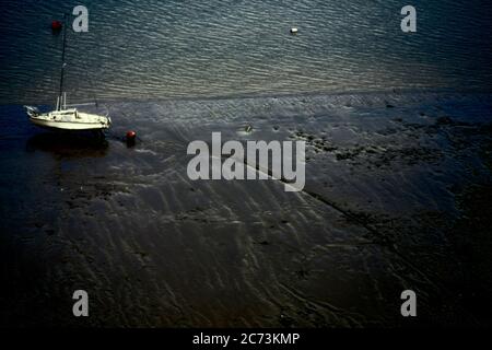 Bateau blanc coincé à la marée basse de la Tamise au bord de la soirée. Banque D'Images