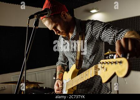 photo en gros plan de guitare électrique, musicien talentueux tient la guitare en main, exécute la musique en studio Banque D'Images