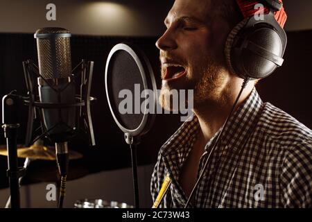 beau caucasien dans studio d'enregistrement. jeune homme chanteur professionnel se préparant avant la performance musicale, concert. homme chauffe les cordes vocales Banque D'Images