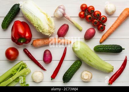 Divers légumes crus sur fond gris. Courgettes, concombre, piment, champignons, tomate, chou-fleur, laitue, carottes, céleri radische à l'ail Banque D'Images