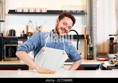 Joueur ravi jeune homme, table propre, exprime l'optimisme, regarde directement la caméra avec le grand sourire, heureux de voir les clients amicaux dans le coff Banque D'Images